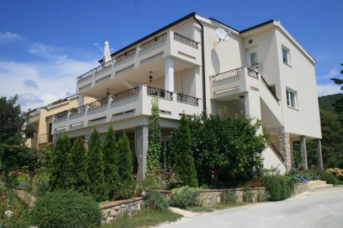 Un gran edificio blanco con árboles delante. en Apartment Aria, en Rab