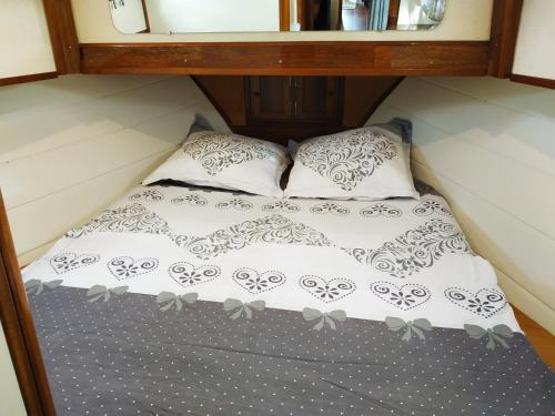 Cama en habitación pequeña con 2 almohadas en Queen Créole Séjour Romantique en Le Gosier