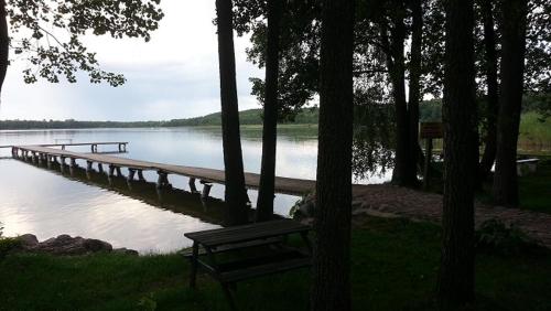 a bench sitting next to a dock on a lake at Domki Letniskowe Kobyłocha in Kobyłocha