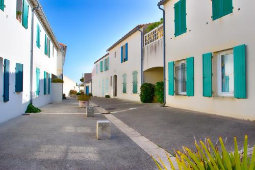 an empty street with white buildings with green shutters at Clos Vauban in Saint-Martin-de-Ré