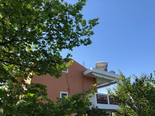 a pink building with trees in the foreground at DISTRiCT 01 -Luxurious Villa with private beach in Metókhion Konstamonítou
