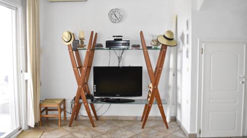 a living room with a tv and a desk with a monitor at DISTRiCT 01 -Luxurious Villa with private beach in Metókhion Konstamonítou