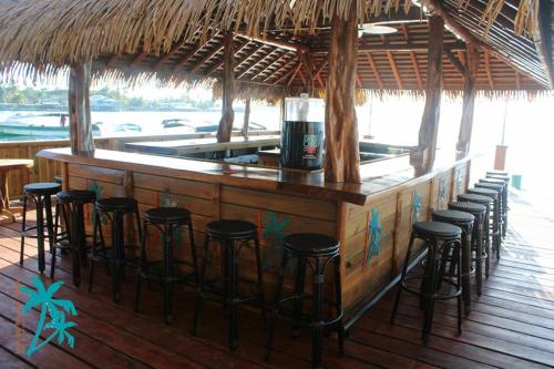 een bar met krukken aan een bar met een drankje bij Hotel Bocas Town in Bocas del Toro