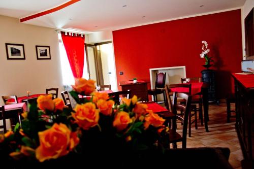 a restaurant with red walls and tables and flowers at Agriturismo Monbertola in Govone