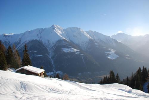 a snow covered mountain with a house in the foreground at Chalet Foresta in Bettmeralp