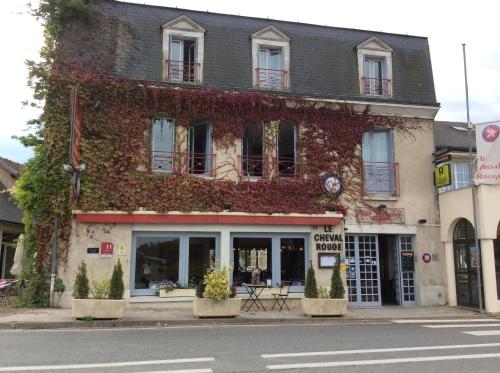 a building covered in ivy on the side of a street at The Originals City, Hôtel Le Cheval Rouge, Tours Ouest in Villandry