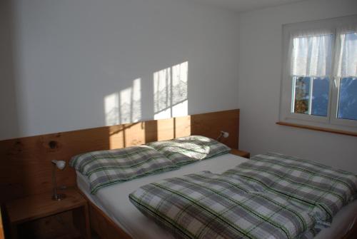 ein Schlafzimmer mit einem Bett mit einer Bettdecke und einem Fenster in der Unterkunft Chalet Foresta in Bettmeralp