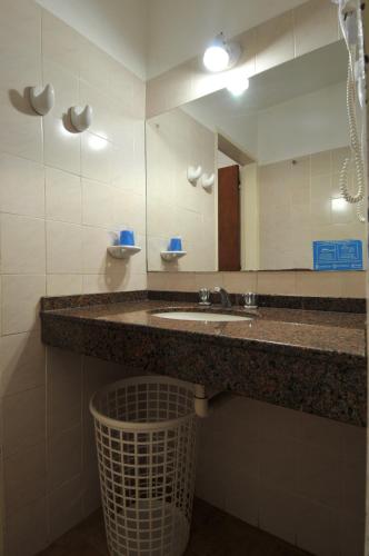 a bathroom with a sink and a mirror and a trash can at Casa Nostra Hotel in Villa Carlos Paz