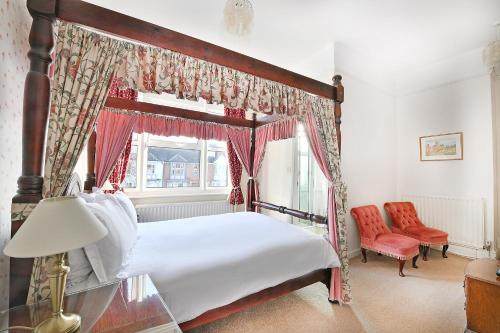 - une chambre avec un lit à baldaquin et une fenêtre dans l'établissement Virginia Lodge, à Stratford-upon-Avon