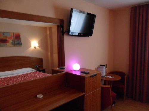 a hotel room with a bed and a television on the wall at Motel Emporio in Cabezón de Pisuerga