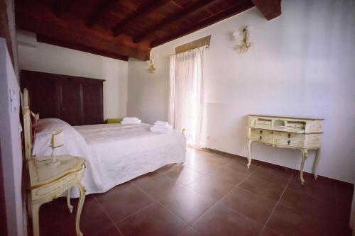 Un dormitorio con una cama blanca y una mesa. en Villa La Lolliana, en Monestirolo