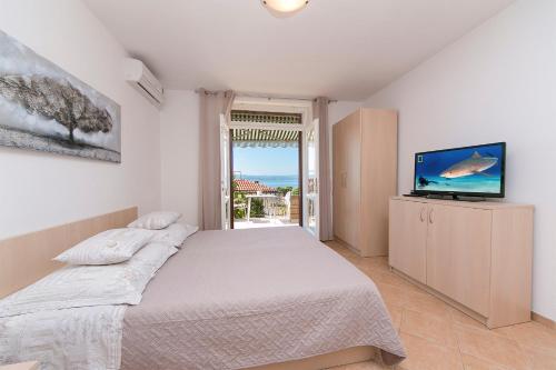 a bedroom with a bed and a tv and a window at Seaview Center House Brela in Brela