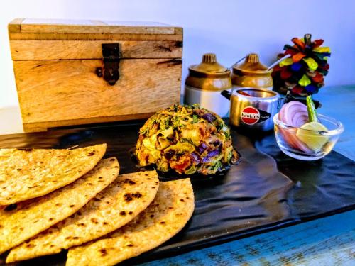 a table topped with a plate of food with pita bread at Parvatah in Bīr