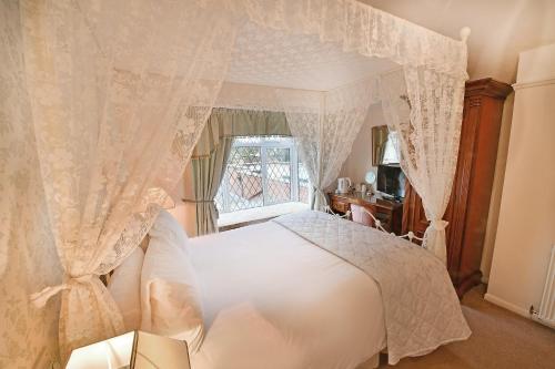 a bedroom with a white bed and a window at Virginia Lodge in Stratford-upon-Avon