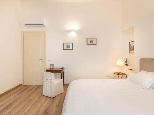a white bedroom with a large bed and a door at B&B Palazzo Merello in Cagliari