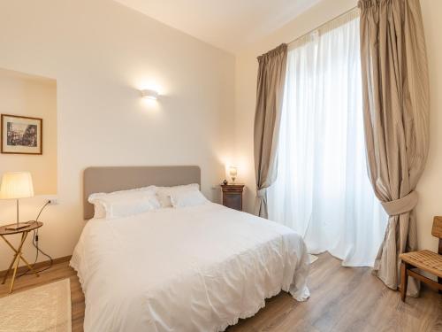 a bedroom with a white bed and a large window at B&B Palazzo Merello in Cagliari