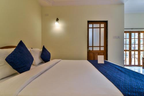 a bedroom with a large white bed with blue pillows at Sonikas Holiday Homes (Studio) in Candolim