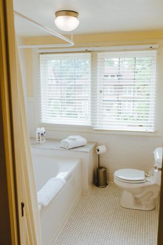 a bathroom with a tub and a toilet and a window at Leonard at Logan House in Grand Rapids