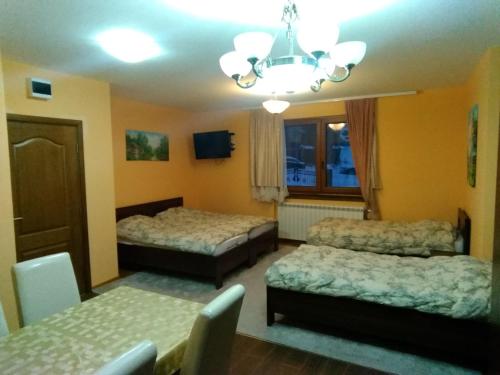 a hotel room with two beds and a chandelier at Apartman Vila Natasa in Kopaonik