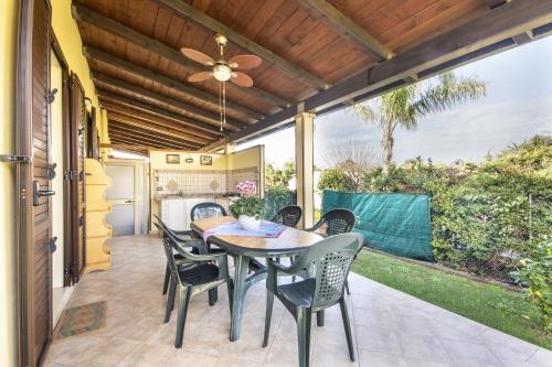 un patio con tavolo, sedie e ventilatore a soffitto di Case Vacanze Paradise Beach Vicino Cefalù PISCINA APERTA a Campofelice di Roccella