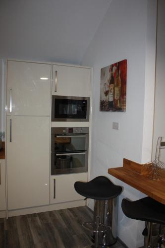 a kitchen with a refrigerator and a table and stools at Ferndown Holiday Let in Ferndown