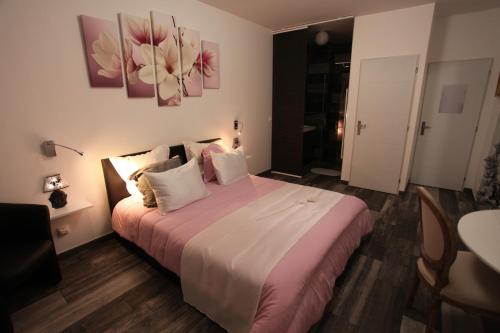 1 dormitorio con 1 cama grande con sábanas y almohadas rosas en le chat botté77, en Jossigny