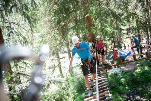 a man walking on a suspension bridge in the forest at App. Tamanhof in San Giorgio
