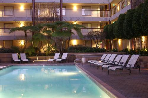 a hotel swimming pool with lounge chairs next to a building at Cupertino Hotel in Cupertino