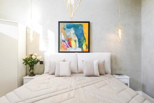 a bedroom with a white bed with a painting on the wall at Duomo Suites Florence in Florence