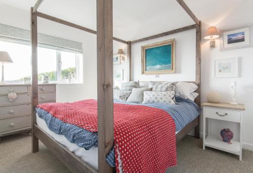 a bedroom with a canopy bed with a red blanket at Creagle, Sennen Cove in Sennen Cove