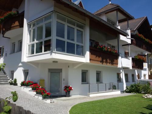 a white house with flowers on the balcony at App. Tamanhof in San Giorgio