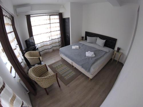 een slaapkamer met een bed en 2 stoelen. bij Cochet Accommodation in Piatra Neamţ
