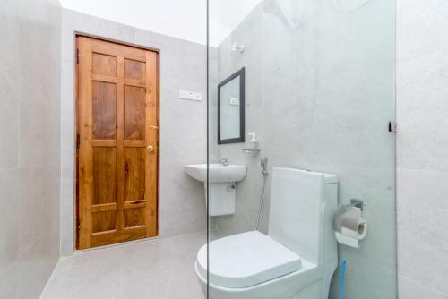 a bathroom with a toilet and a wooden door at Estancia Holiday Bungalow in Matale
