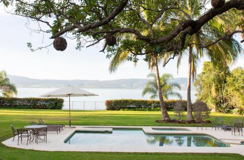 uma piscina com mesas, cadeiras e um guarda-sol em Las Palomas Bed & Breakfast (16 y Mayores) em San Juan Cosalá