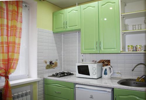 a kitchen with green cabinets and a microwave at Apartment on Sportivnaya in Bender