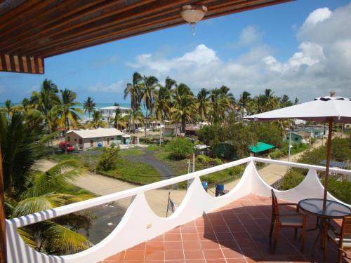 a balcony with a view of the beach and palm trees at Hotel La Laguna Galapagos in Puerto Villamil