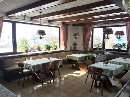 un ristorante con tavoli, sedie e ampie finestre di Pension Berghof a Schönsee