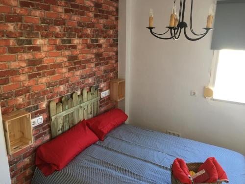 Un dormitorio con una pared de ladrillo y una cama con almohadas rojas. en Monkey Room en La Línea de la Concepción