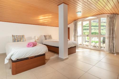 - une chambre avec 2 lits et une grande fenêtre dans l'établissement Apartment lucy, à Arco da Calheta