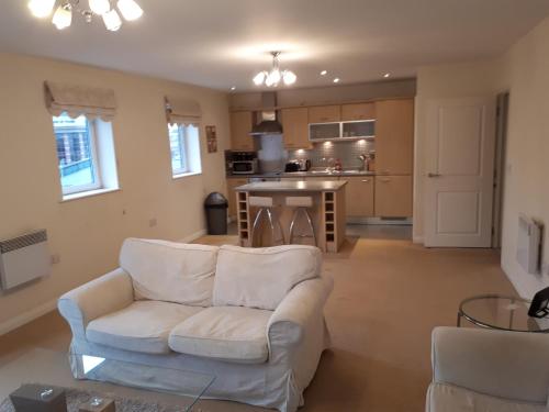 a living room with a white couch and a kitchen at Solihull centre apartments in Solihull