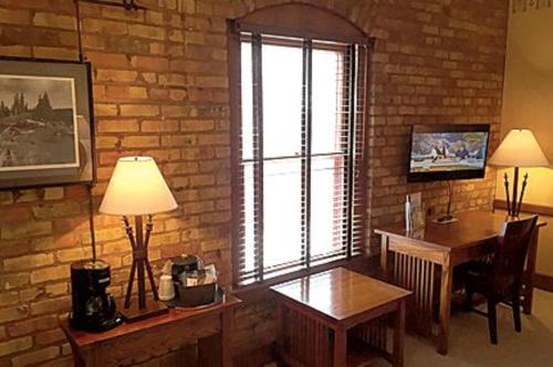 a room with a brick wall with a table and a window at The Branch House in Deadwood