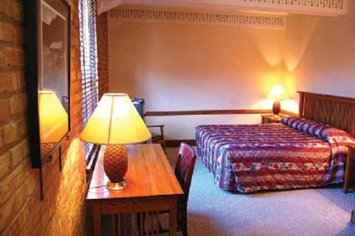 a hotel room with a bed and a table with a lamp at The Branch House in Deadwood