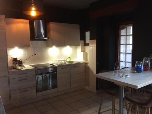 a kitchen with white cabinets and a table with chairs at Appartement Orion in Colmar