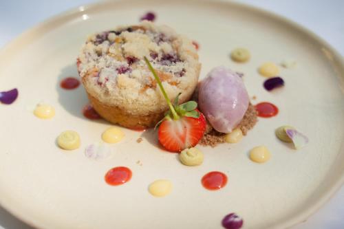 a plate with a muffin and a strawberry on it at Farmhouse Inn in Forestville