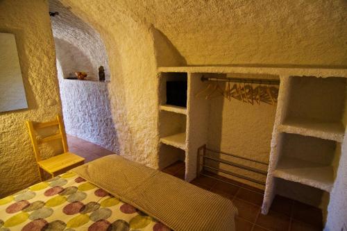een slaapkamer met een bed en planken in een kamer bij Cueva Pura Vida in Pulpite