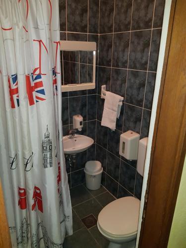 a bathroom with a toilet and a sink and a shower curtain at Motel Magistrala in Doboj