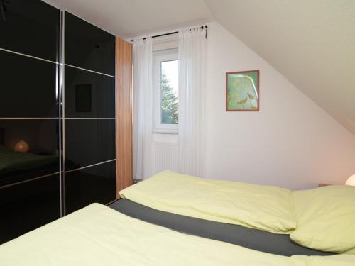 ein kleines Schlafzimmer mit einem Bett und einem Fenster in der Unterkunft Kiebitznest in Krummhörn