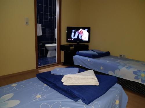 two beds in a room with a tv and a bathroom at Motel Magistrala in Doboj