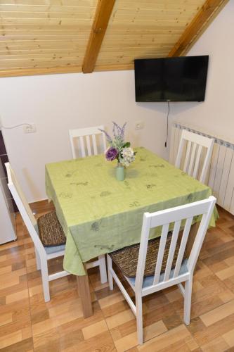 a table and chairs with a green table and a television at Apartmani Miščević in Josipdol