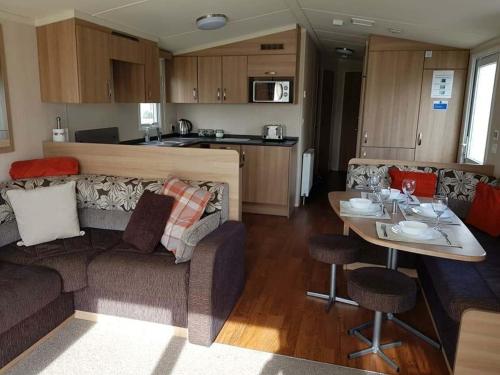 a living room and kitchen with a couch and a table at Flamingo land le maple grove caravan hire in Kirby Misperton